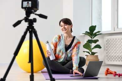 Happy sports blogger recording fitness lesson with camera at home