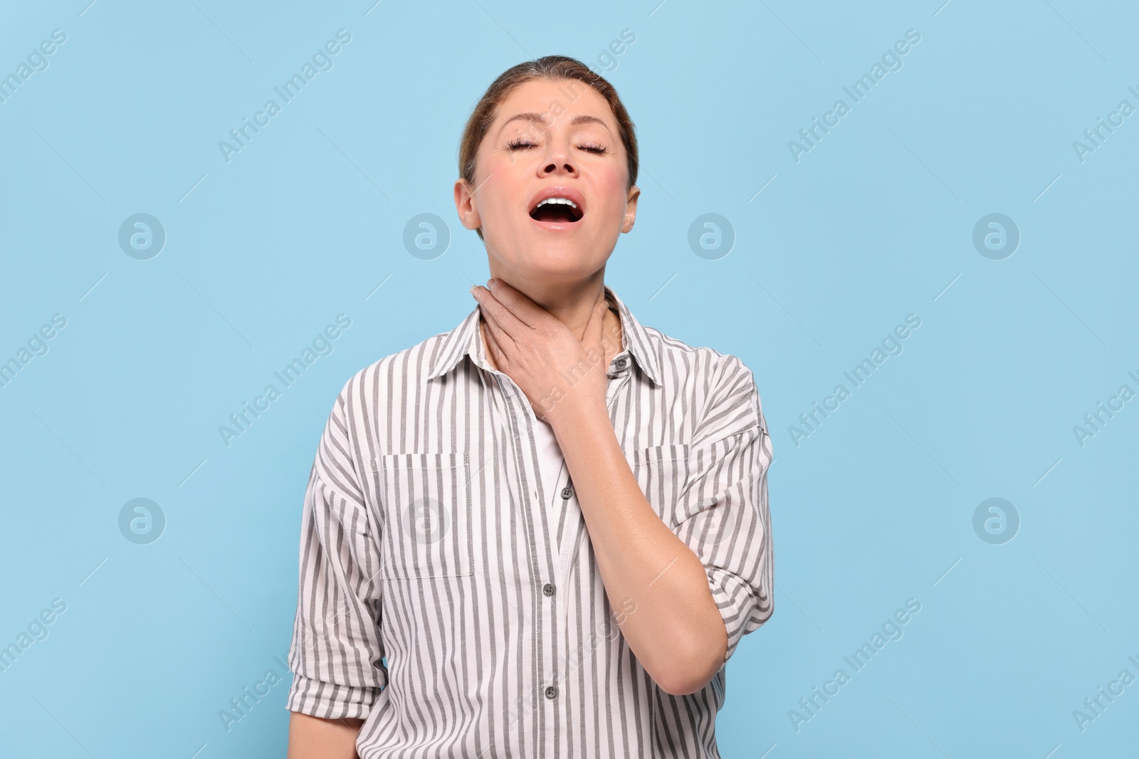 Photo of Woman suffering from sore throat on light blue background