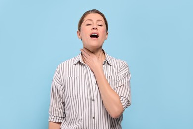 Photo of Woman suffering from sore throat on light blue background