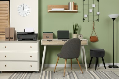 Photo of Stylish workplace with laptop and modern printer indoors