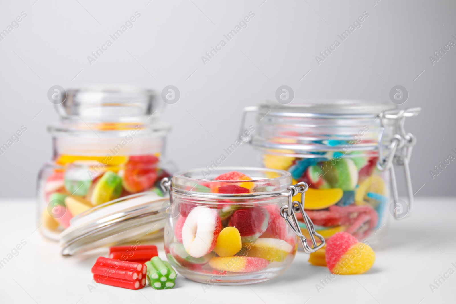 Photo of Tasty jelly candies in jars on white table