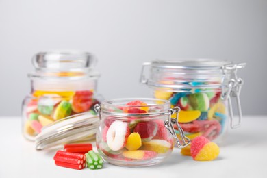 Photo of Tasty jelly candies in jars on white table