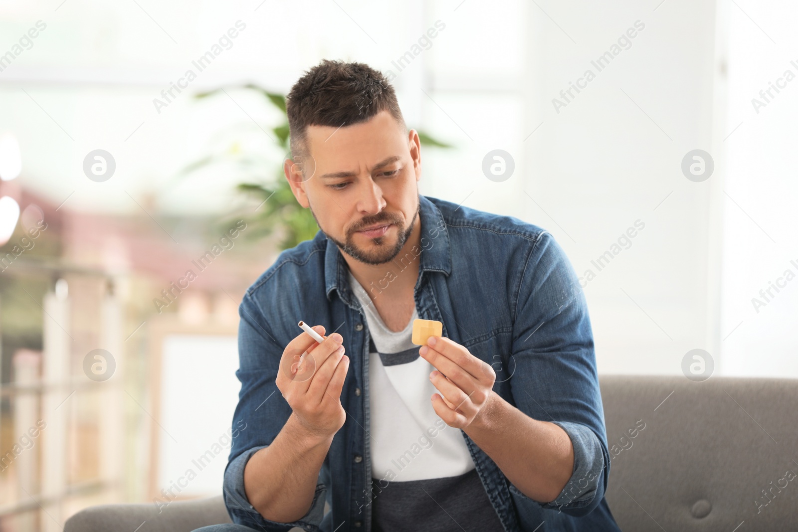 Photo of Man with nicotine patch and cigarette at home