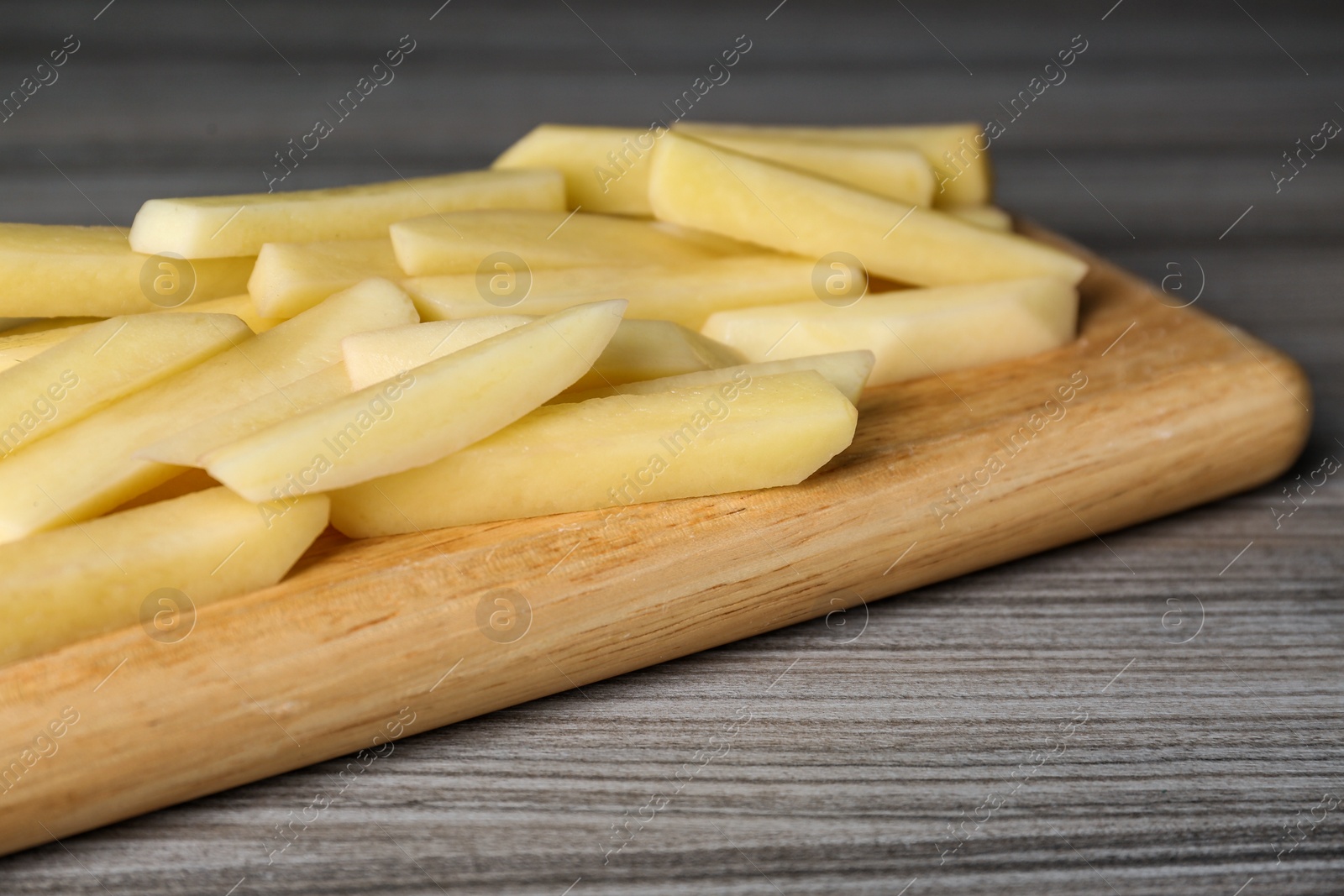 Photo of Cut raw potatoes on wooden table, closeup