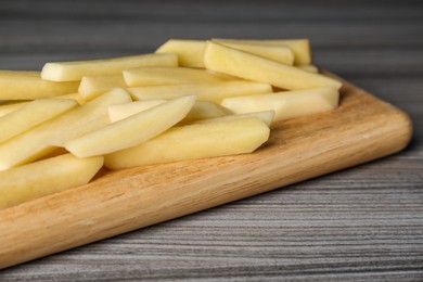 Photo of Cut raw potatoes on wooden table, closeup