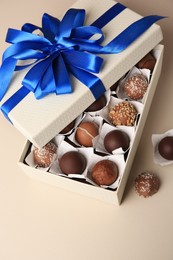 Photo of Box with delicious chocolate candies on beige background, above view