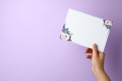 Photo of Woman holding blank invitation card on lilac background, closeup. Space for text