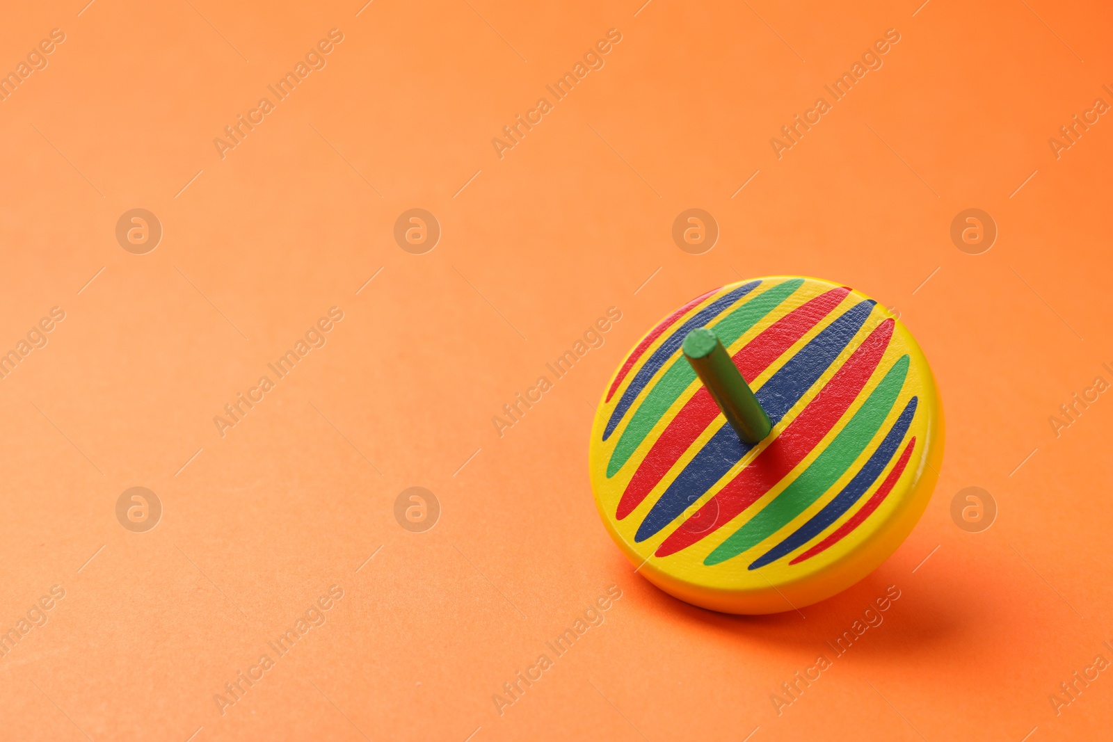 Photo of One colorful spinning top on orange background, space for text