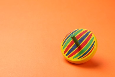 Photo of One colorful spinning top on orange background, space for text