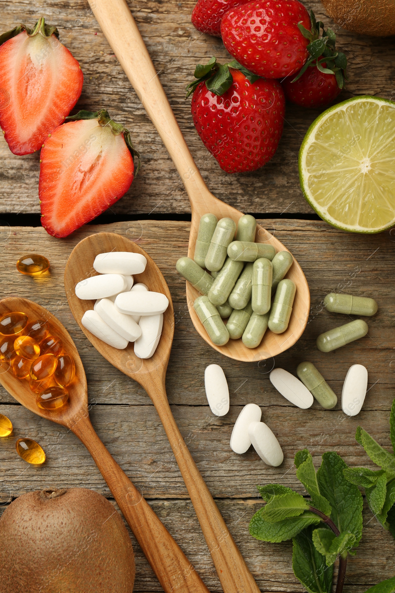 Photo of Different vitamin pills and fresh fruits on old wooden table, flat lay