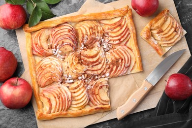 Photo of Tasty apple pie with nuts, fresh fruits and knife on black table, flat lay