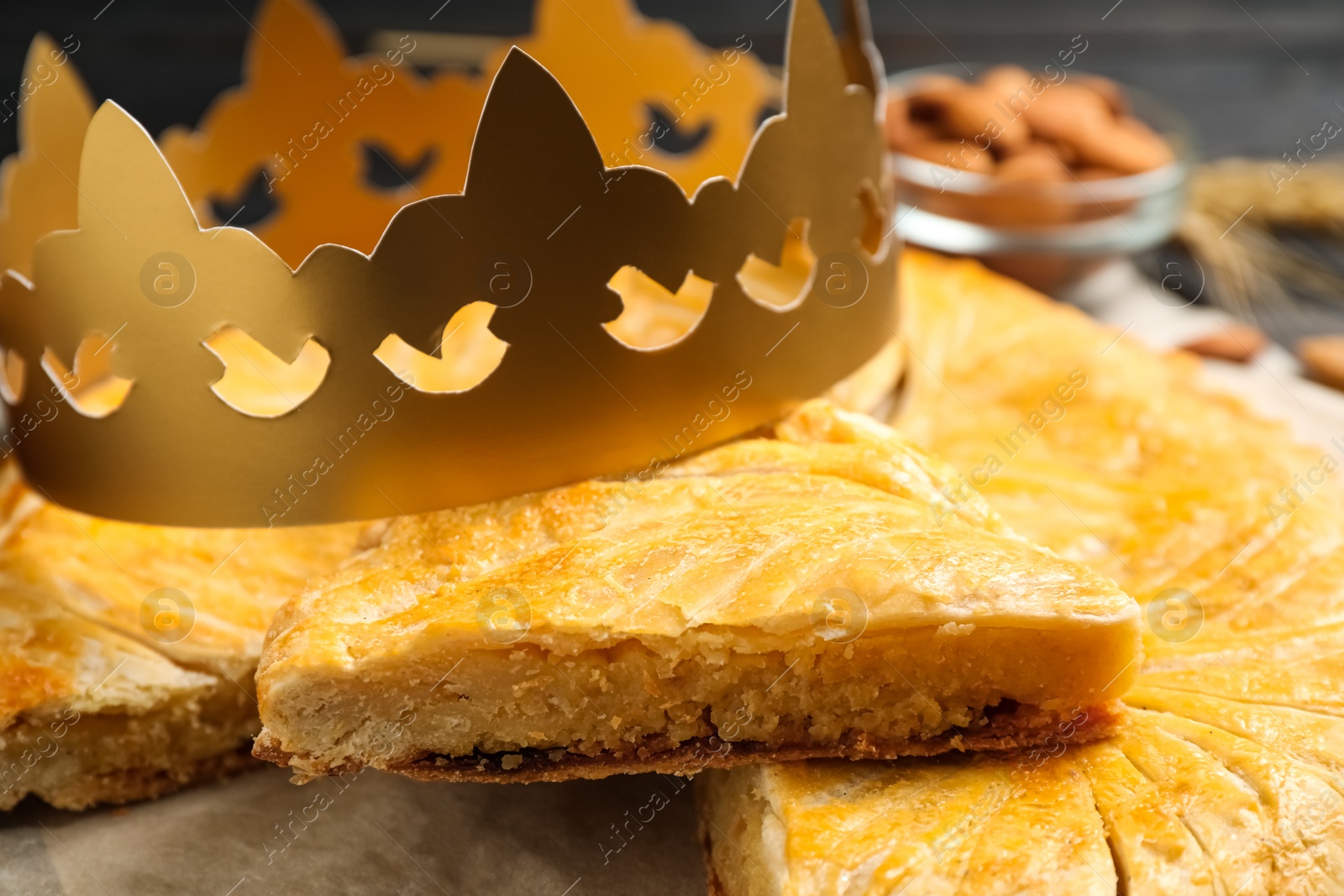 Photo of Traditional galette des Rois with paper crown on table, closeup