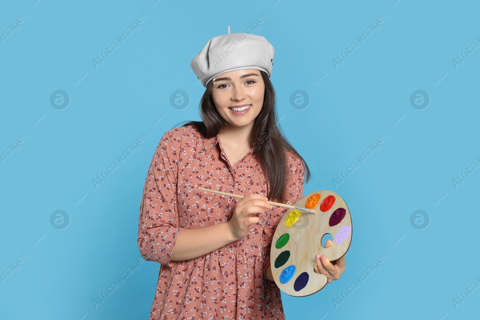 Photo of Woman with painting tools on light blue background. Young artist