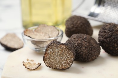 Photo of Whole and cut black truffles on table, closeup