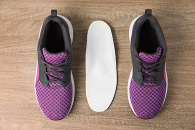 Photo of Orthopedic insole near shoes on floor, flat lay