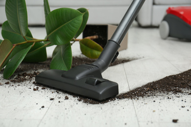 Photo of Removing soil from wooden floor with vacuum cleaner at home, closeup