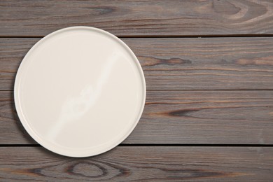 Photo of One ceramic plate on grey wooden table, top view. Space for text