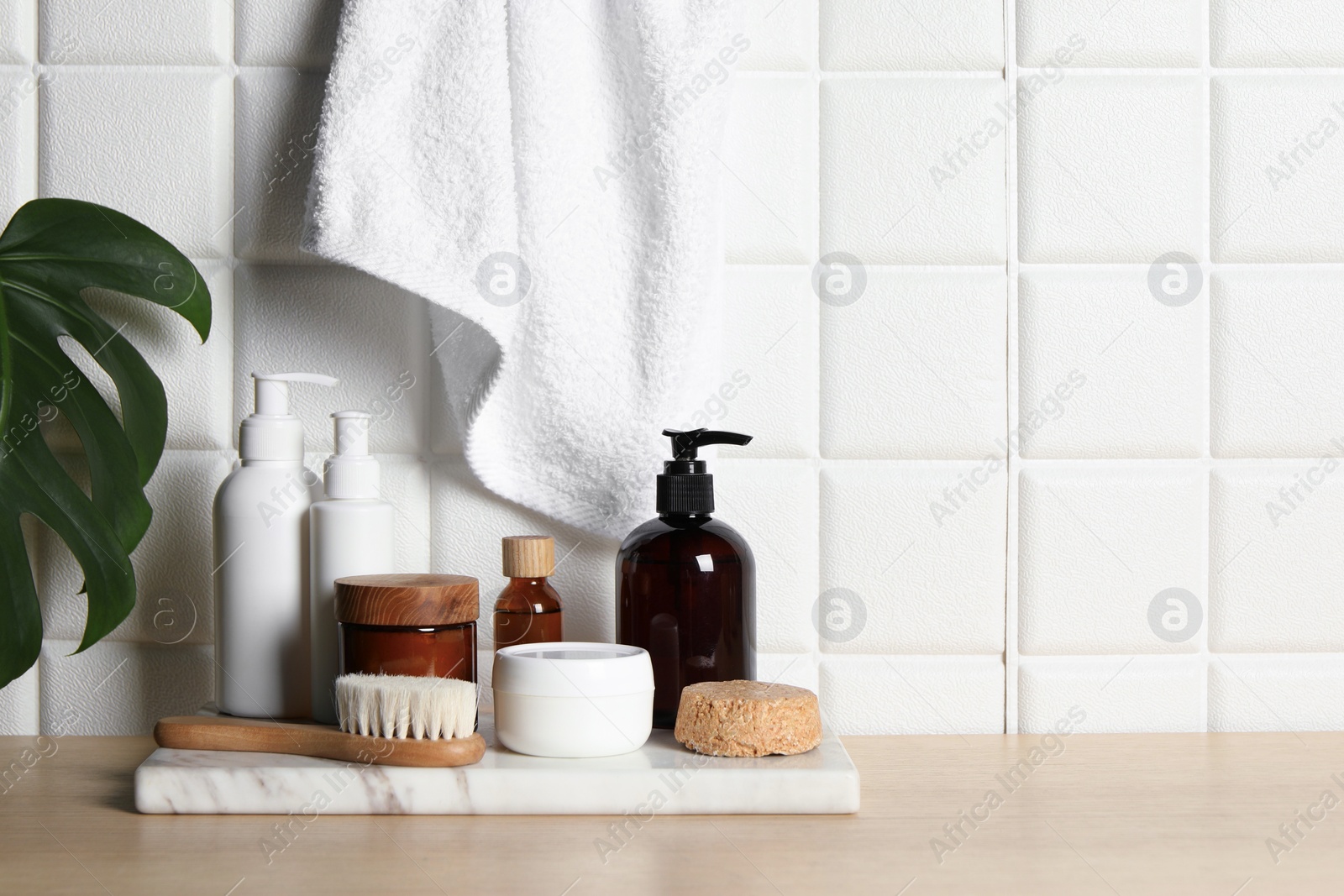 Photo of Different bath accessories and personal care products on wooden table near white tiled wall, space for text