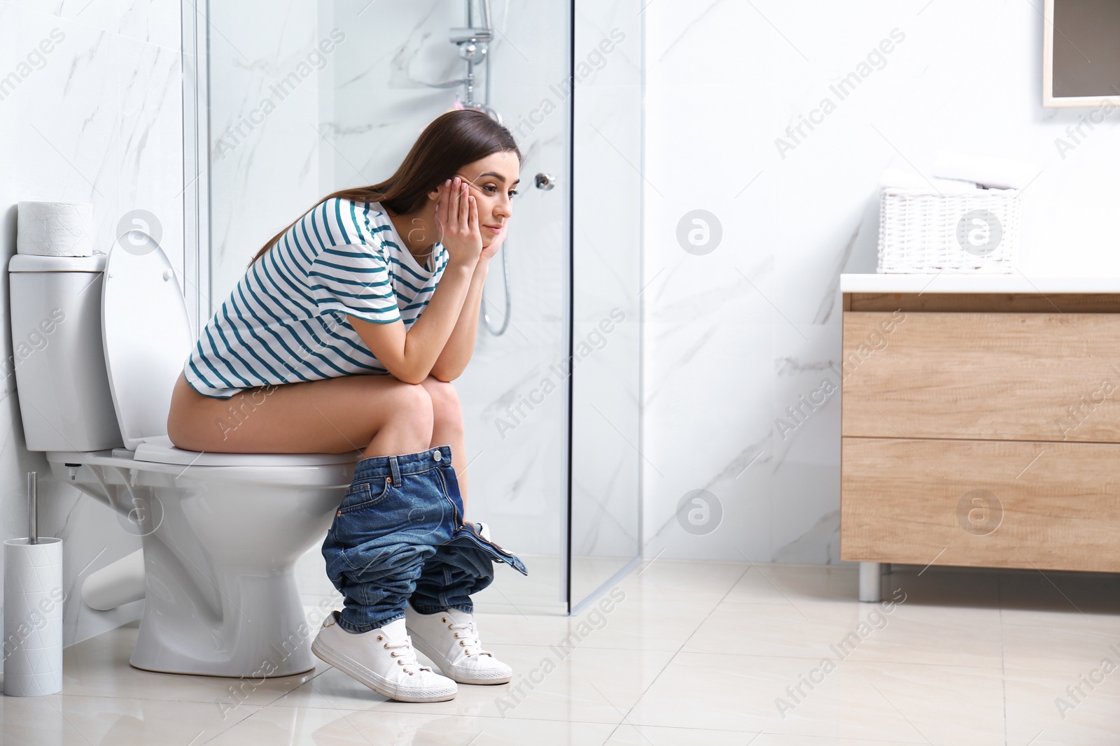 Photo of Upset woman sitting on toilet bowl in bathroom