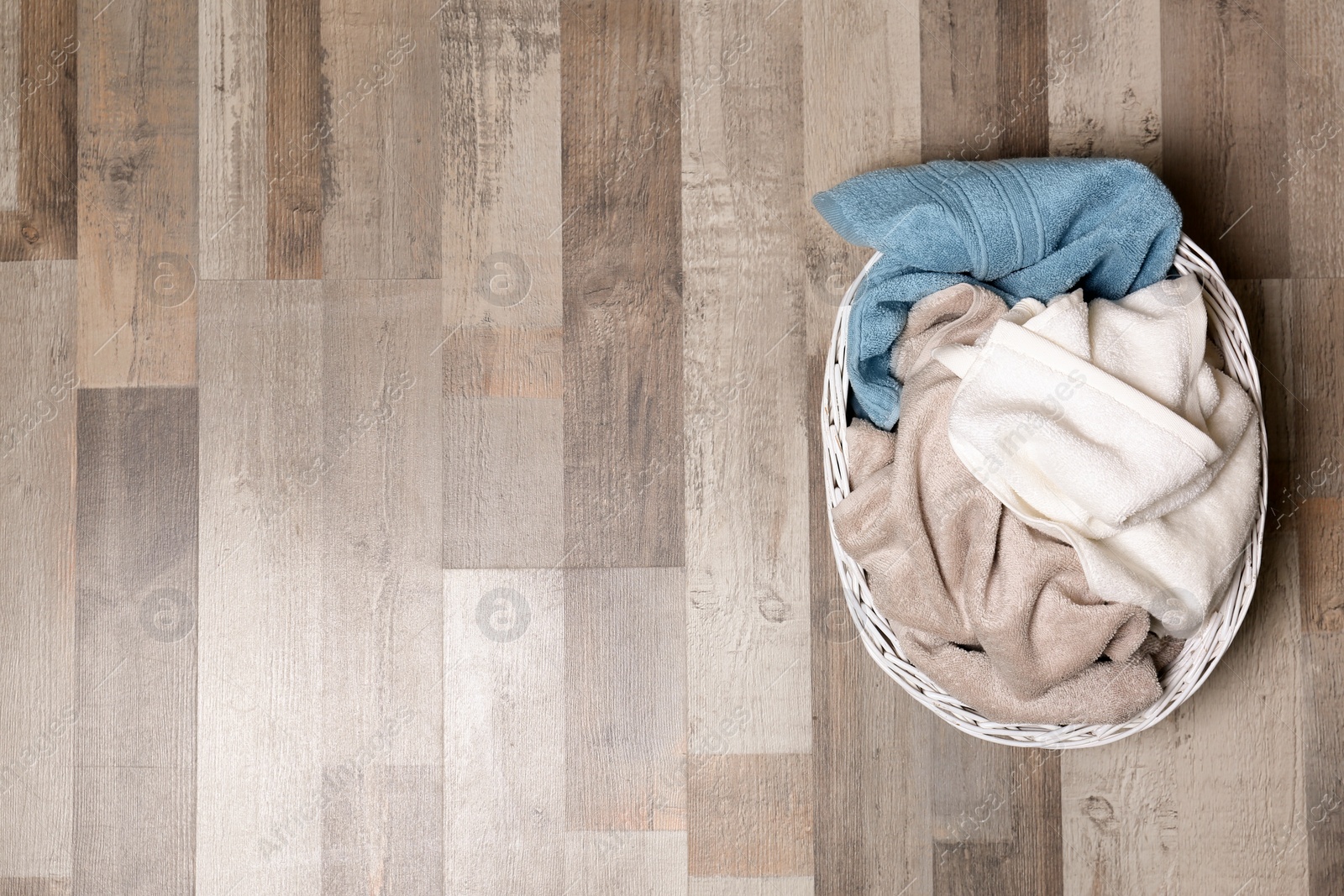 Photo of Laundry basket with dirty clothes on floor, top view. Space for text