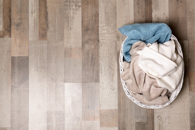 Laundry basket with dirty clothes on floor, top view. Space for text