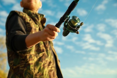 Photo of Fisherman with rod fishing under blue sky, closeup. Space for text