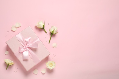 Photo of Elegant gift box and beautiful flowers on pink background, flat lay. Space for text
