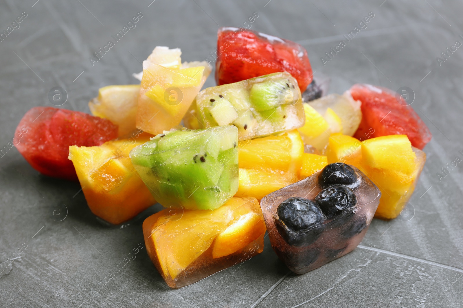 Photo of Fruit and berry ice cubes on grey background
