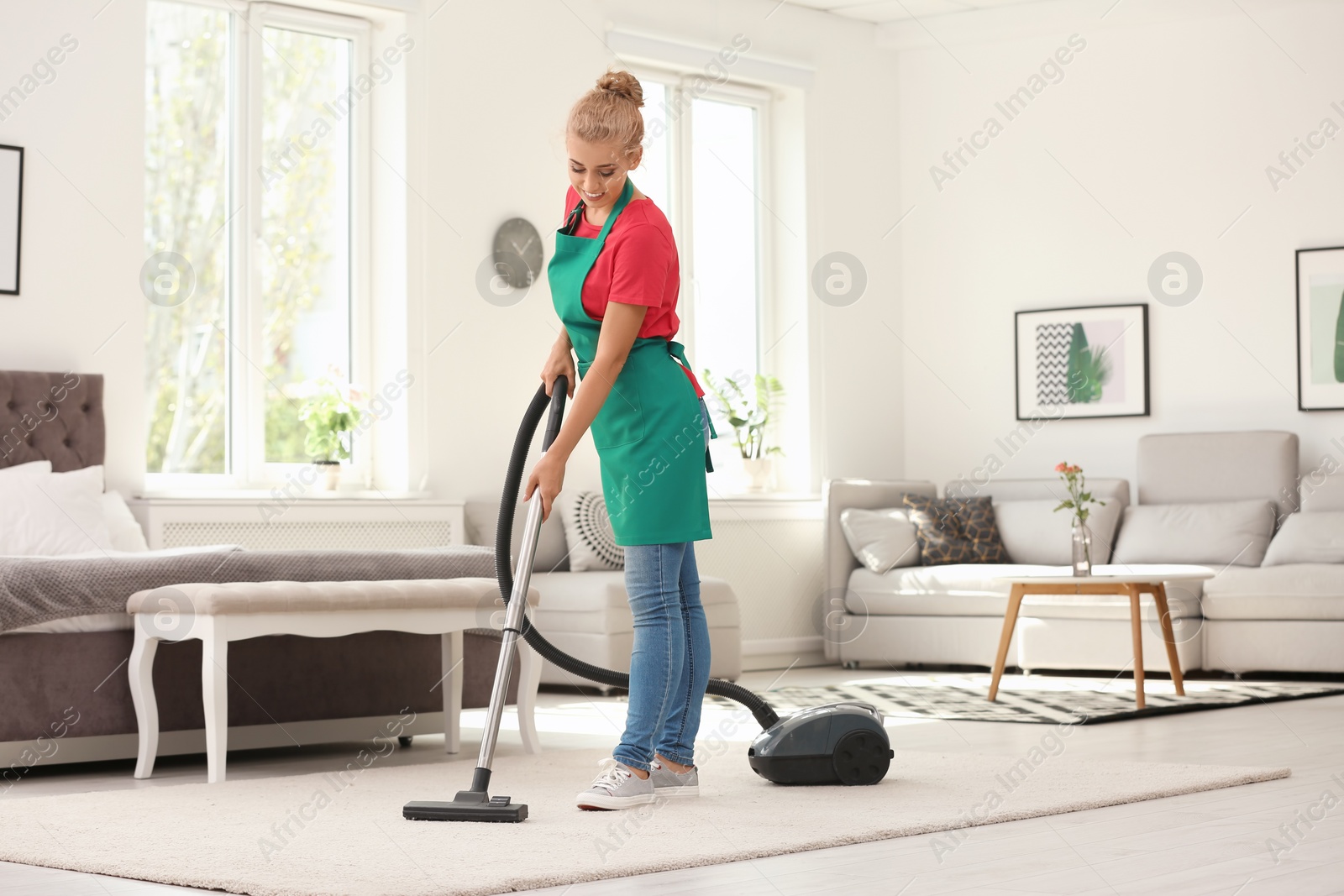 Photo of Woman removing dirt from carpet with vacuum cleaner indoors