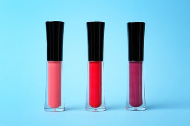 Photo of Beautiful lip glosses on color background