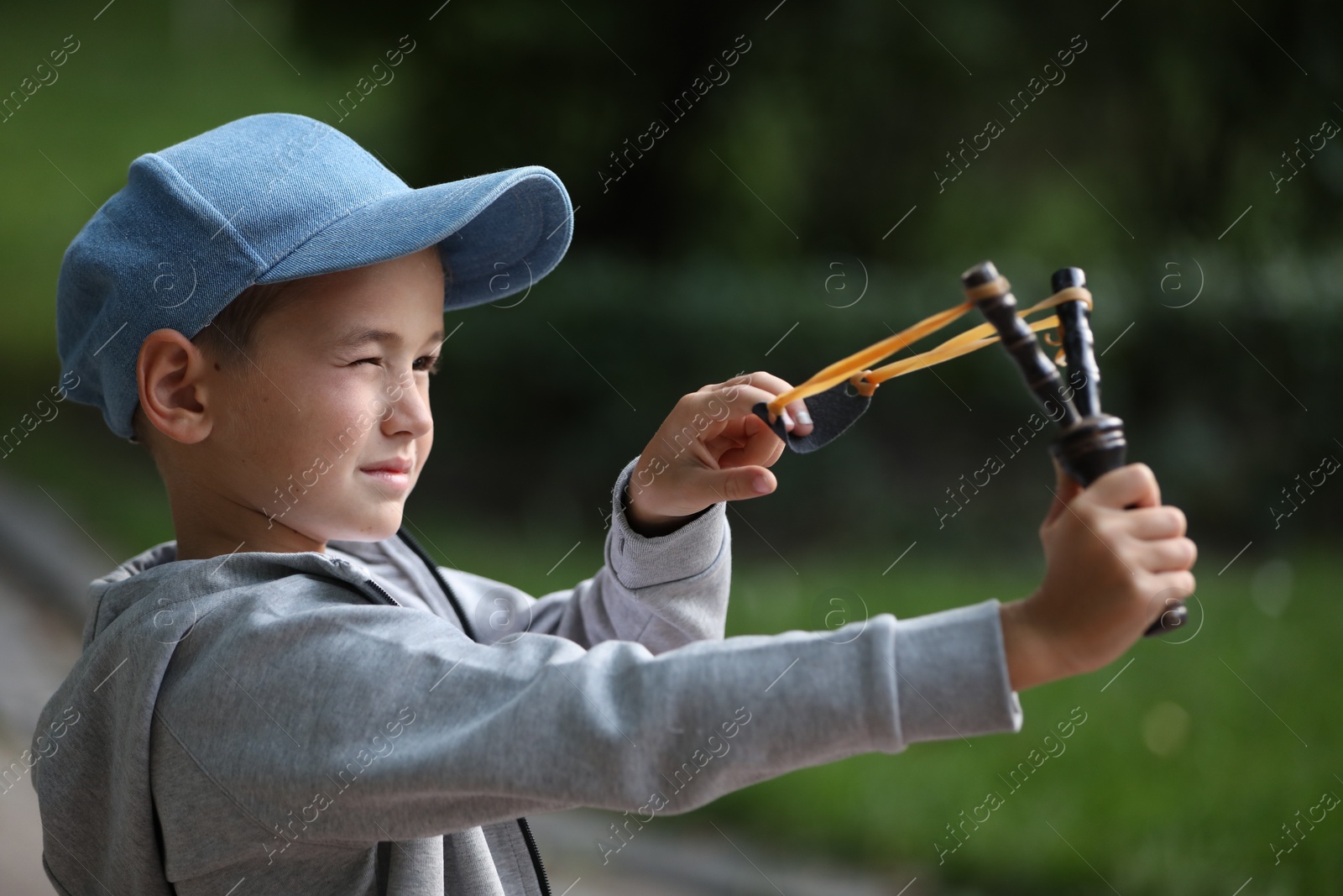 Photo of Little boy playing with slingshot in park