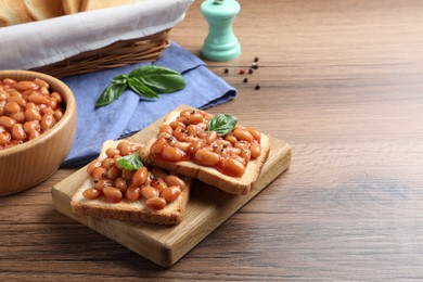 Toasts with delicious canned beans on wooden table, space for text