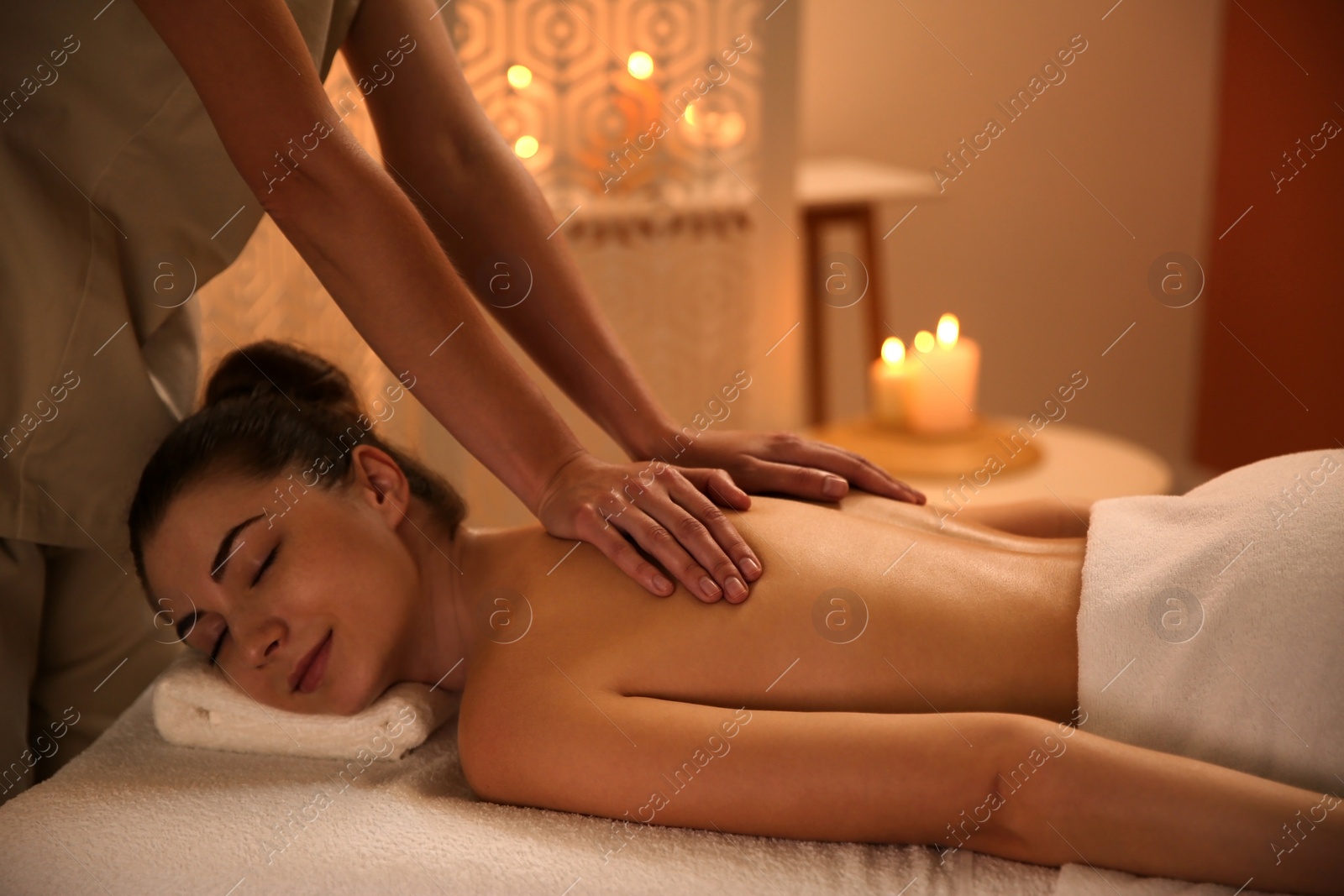 Photo of Young woman receiving back massage in spa salon