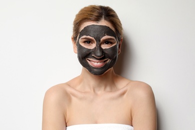 Photo of Beautiful woman with black mask on face against light background