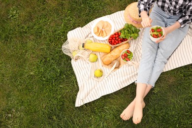 Photo of Girl having picnic on green grass in park, above view