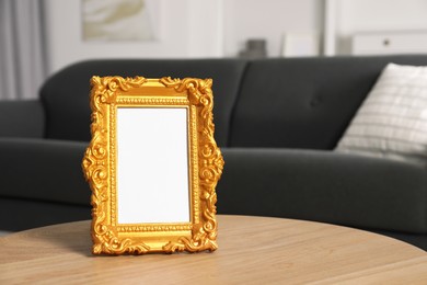 Beautiful golden vintage frame on wooden coffee table indoors, space for text