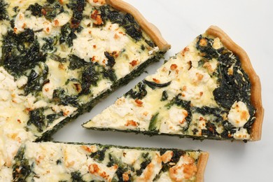 Delicious homemade spinach quiche on white table, flat lay