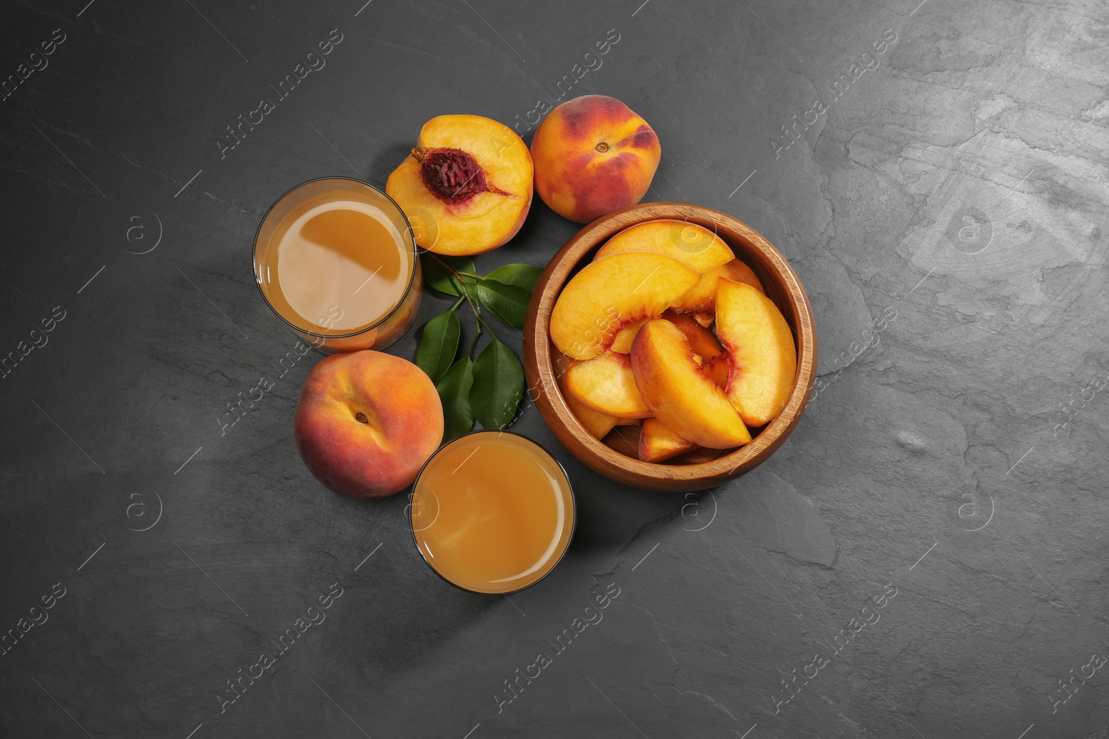 Photo of Glasses of delicious peach juice, fresh fruits and leaves on black table, flat lay