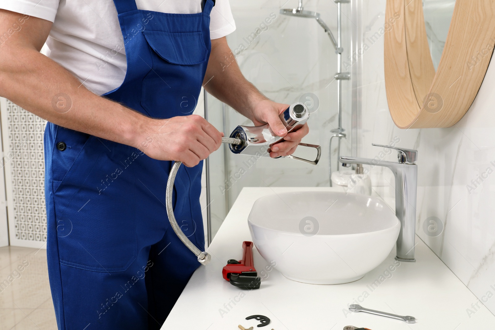 Photo of Professional plumber fixing water tap in bathroom, closeup