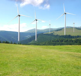 Image of Alternative energy source. Wind turbines in mountains under blue sky