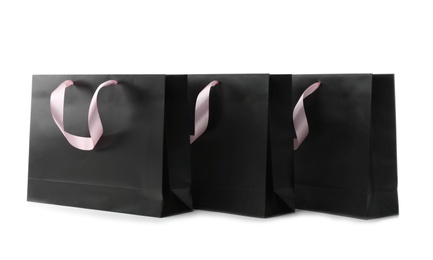 Paper shopping bags with ribbon handles on white background. Mockup for design