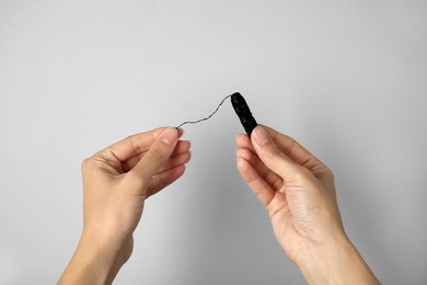 Photo of Woman holding biodegradable dental floss against light background, closeup