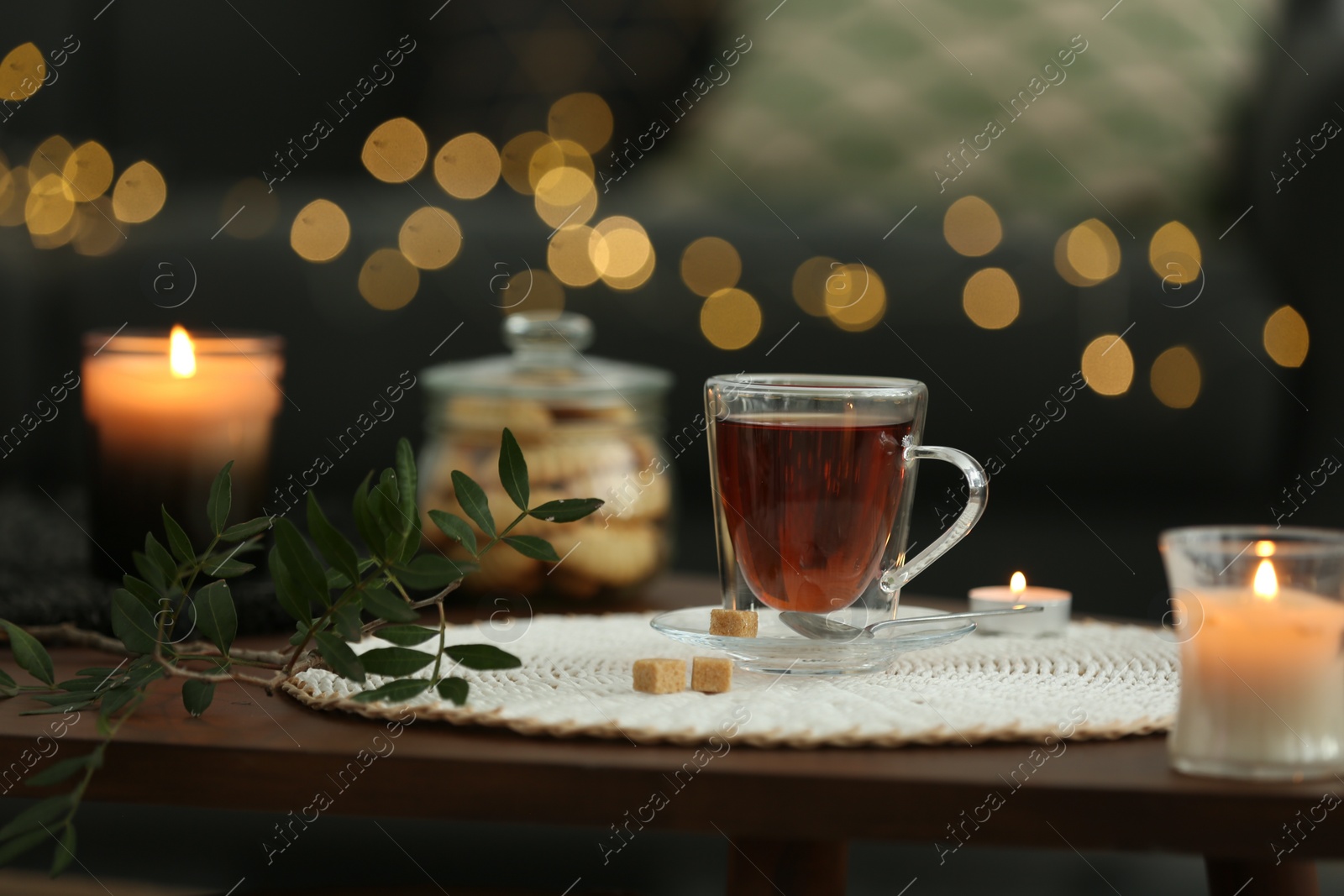 Photo of Tea, cookies and decorative elements on wooden table against blurred lights indoors