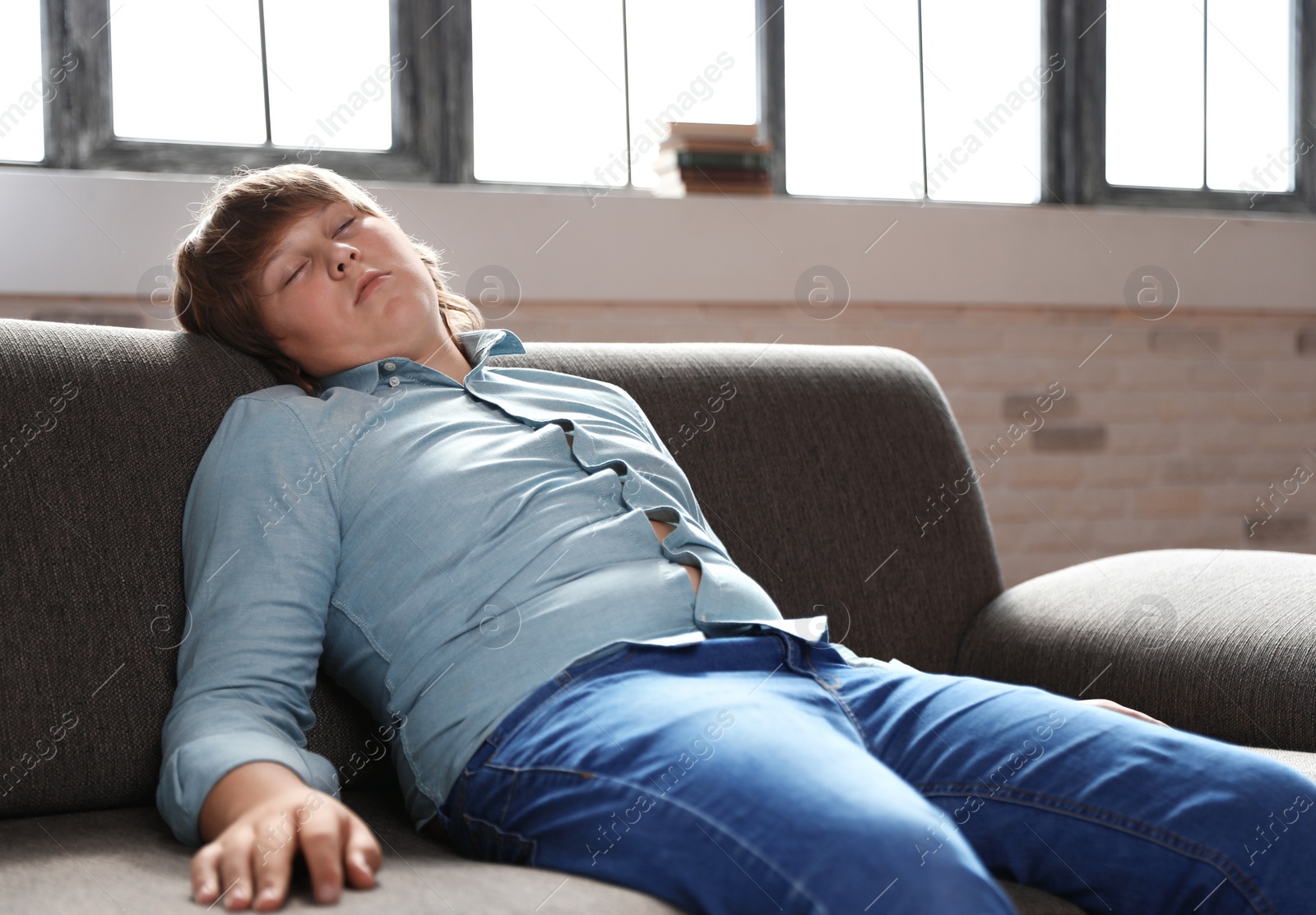 Photo of Overweight boy sleeping on sofa at home