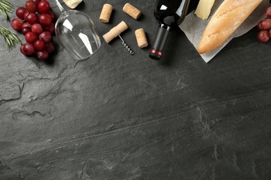 Flat lay composition with red wine and snacks on black table, space for text