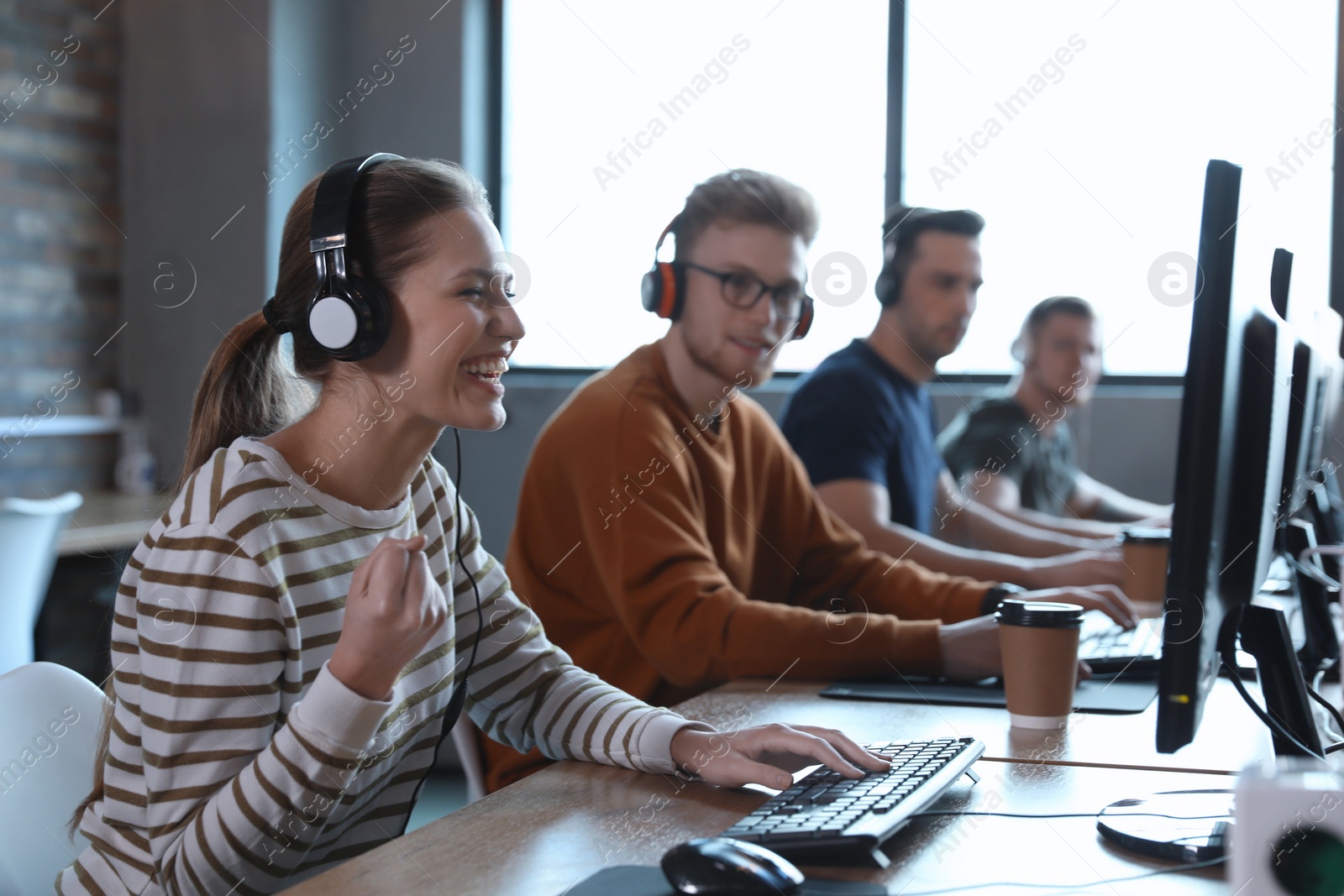 Photo of Group of people playing video games in internet cafe