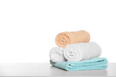 Soft colorful terry towels on light table against white background, space for text