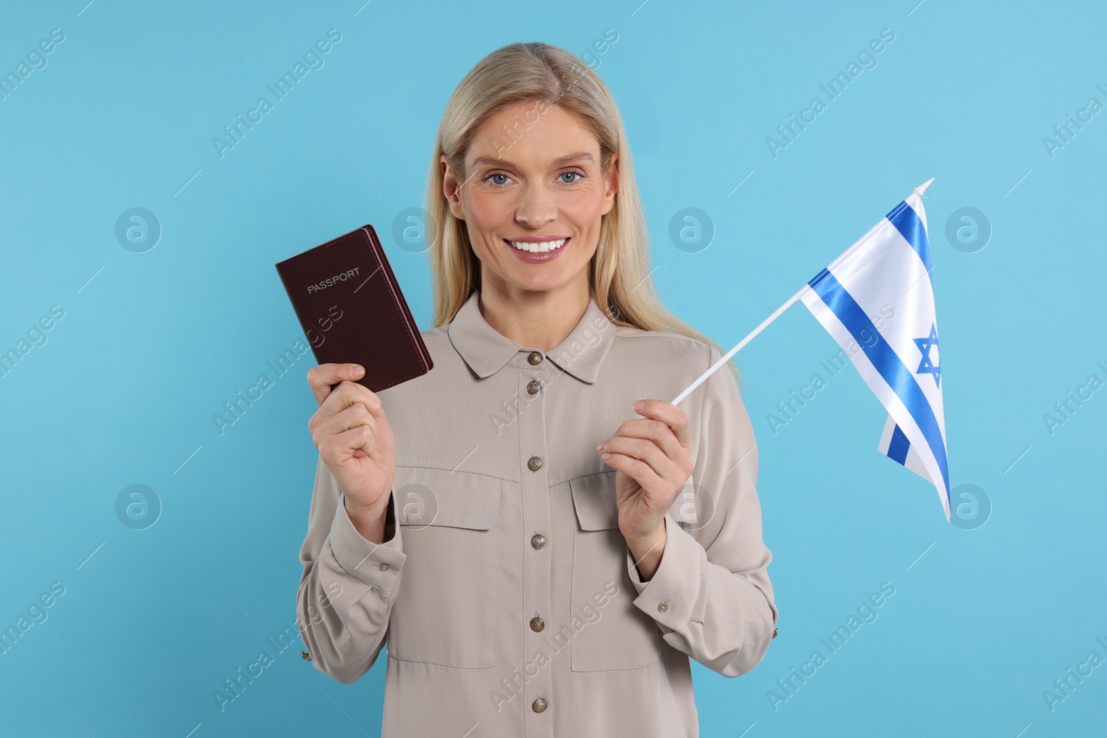 Photo of Immigration. Happy woman with passport and flag of Israel on light blue background