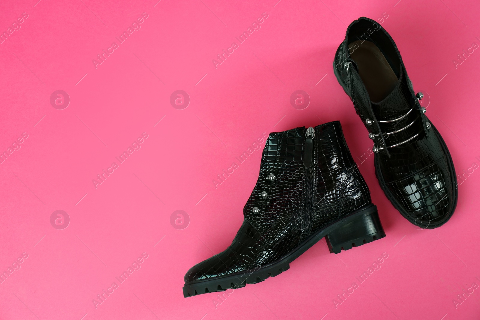 Photo of Pair of stylish ankle boots on pink background, top view. Space for text