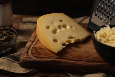 Photo of Piece of cheese on wooden board, closeup